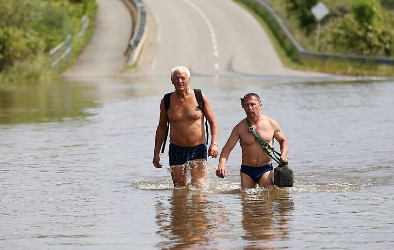 Zwei Männer laufen auf einer von der Elbe überfluteten Straße in Schönhausen (Sachsen-Anhalt).