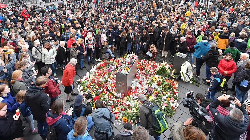 Halle: Menschen stehen auf dem Marktplatz neben Blumen und Kerzen, um ein Zeichen gegen Gewalt zu setzen und um zu Trauern. Bei Angriffen mitten in Halle an der Saale in Sachsen-Anhalt sind am 09.10.2019 zwei Menschen erschossen worden.