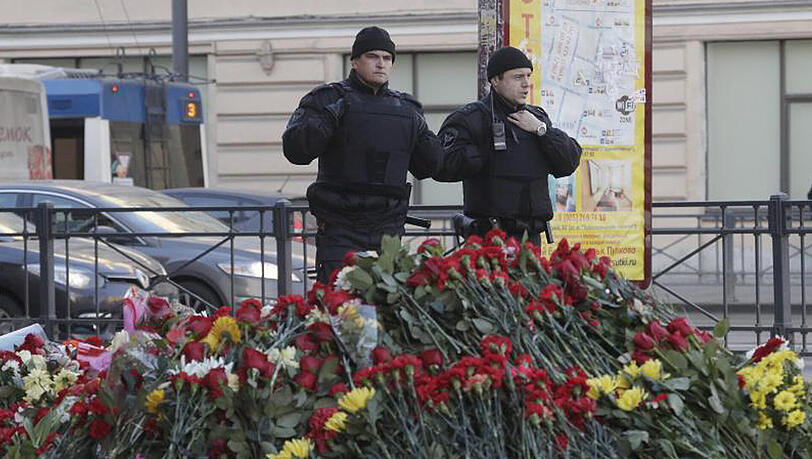 Polizisten vor einer mit Blumen geschmückten Gedenkstätte an der U-Bahn-Station "Technologicheskiy Institute" in St. Petersburg. Polizisten vor einer mit Blumen geschmückten Gedenkstätte an der U-Bahn-Station "Technologicheskiy Institute" in St. Petersburg.