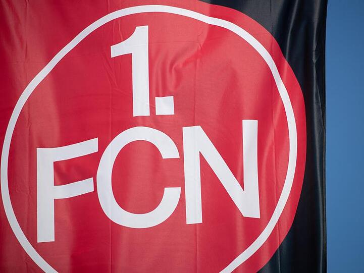 Eine Vereinsfahne mit dem Logo des 1. FC Nürnberg weht im Wind. Foto: Daniel Karmann/dpa/Symbolbild