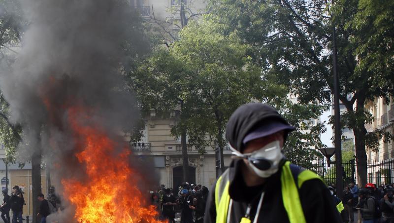 Ein Anhänger der "Gelbwesten" geht in Paris während einer Demonstration an brennenden Gegenständen vorbei. Ein Anhänger der "Gelbwesten" geht in Paris während einer Demonstration an brennenden Gegenständen vorbei.