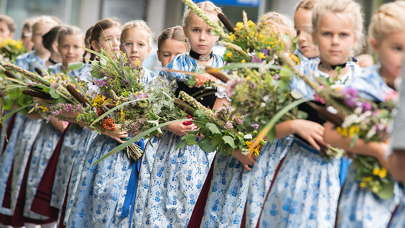 In Tracht gekleidete Mädchen tragen an Mariä Himmelfahrt in Kochel am See Kräuterbuschen in die Kirche.