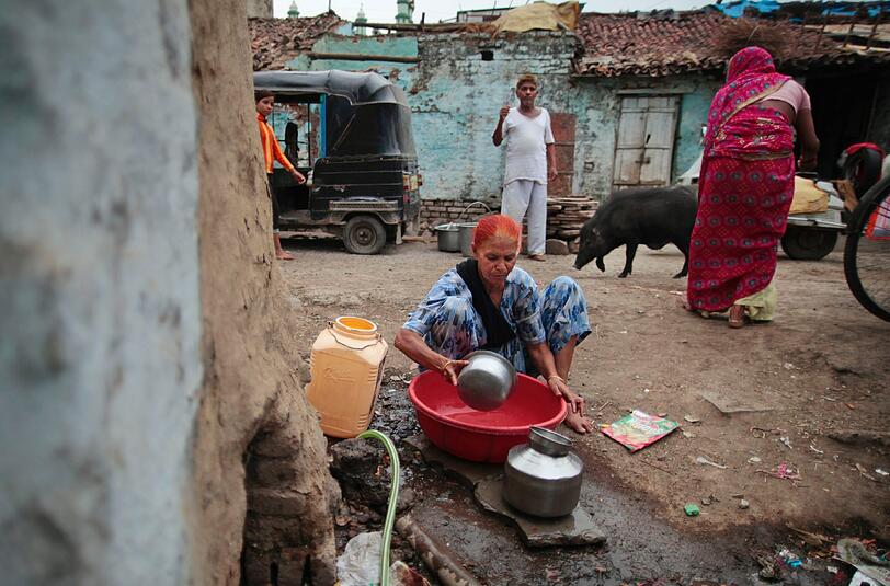 Fatima Munshi sammelt ausserhalb ihres Heims in Khandwa, Indien, Wasser fuer den taeglichen Gebrauch