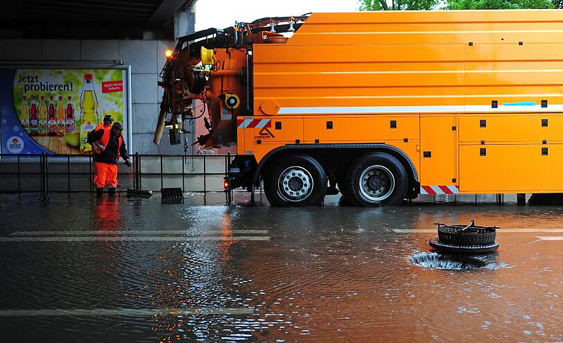 Mitarbeiter der Stadt öffnen am Donnerstag (30.06.2011) in München (Oberbayern) in einer S-Bahn-Unterführung mehrere Kanaldecke, um über die Schächte das Wasser abfließen zu lassen. Heftige Regenfälle in und um München haben für zahlreiche Einsätze bei der Feuerwehr gesorgt.