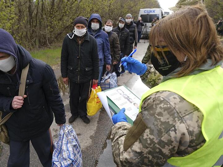 Gefangene mit Mundschutz werden registriert.