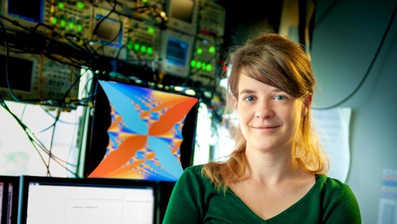 Die Experimentalphysikerin Monika Aidelsburger steht vor Bildschirmen in einem Labor.