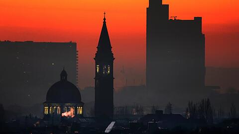 St. Ursula im ersten Morgenlicht: Kuppel und Campanile funkeln, das Hypo-Hochhaus rechts liegt noch im Dunkeln - eingefangen vom Olympiaberg aus.
