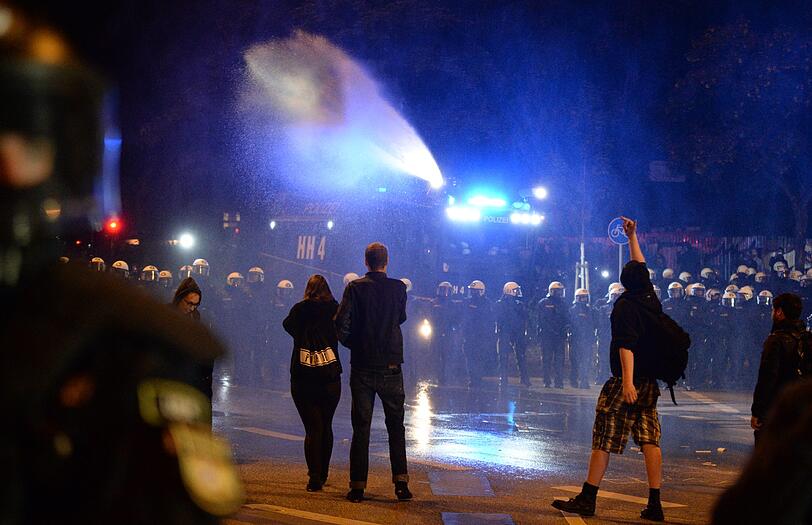 Polizeibeamte und ein Wasserwerfer rücken in Hamburg am Neuen Pferdemarkt im Stadtteil St. Pauli auf der Straße vor. Hunderte Menschen hielten sich auf der Straße auf und behinderten den Verkehr, ehe die Polizei begann, den Neuen Pferdemarkt zu räumen