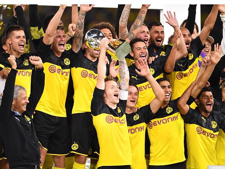 Dortmunds Marco Reus (M) bejubelt mit seinem Trainer Lucien Favre (l) und Mitspielern den Gewinn des Supercups 2019.