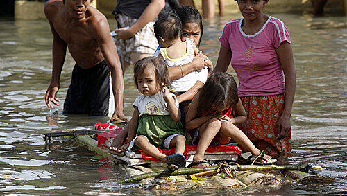 In Manila setzen Eltern ihre Kinder auf selbstgebautes Floß, um sie durch die Fluten zu bringen In Manila setzen Eltern ihre Kinder auf selbstgebautes Floß, um sie durch die Fluten zu bringen