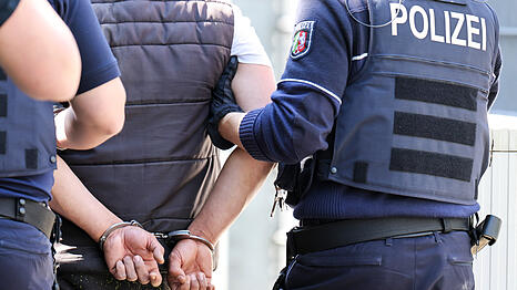 Polizeibeamte führen eine Person nach Randale ab und bringen sie in die Psychiatrie. (Symbolbild)