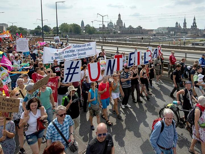 Vor der historischen Altstadtkulisse gehen Tausende Teilnehmer der Demonstration des Bündnisses #Unteilbar über die Carolabrücke in Dresden.