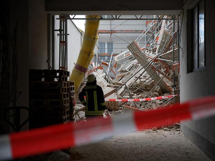 Einsatzkräfte der Feuerwehr stehen in einer Hauseinfahrt.