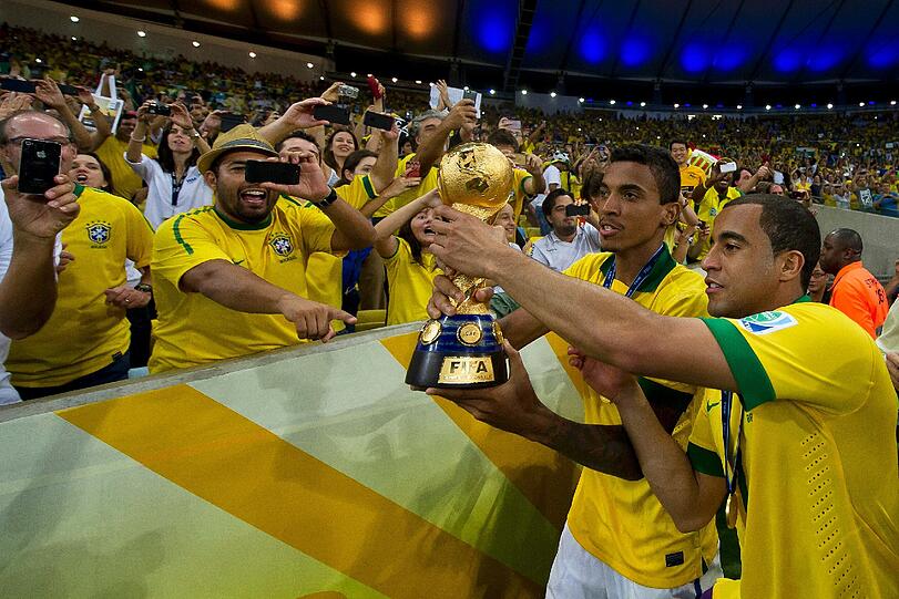 Da ist das Ding: Die Bayern-Stars Luiz Gustavo und Dante feiern nach dem 3:0 gegen Spanien mit dem Pokal, den sie mit der brasilianischen Nationalmannschaft geholt haben.