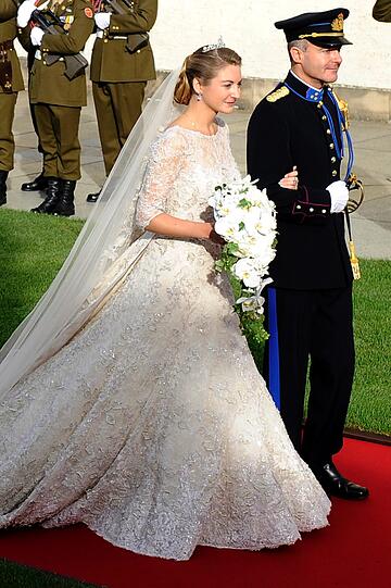 Die Braut erschien in einem elfenbeinfarbenen Brautkleid des Designers Elie Saab mit Diadem und langer Schleppe.