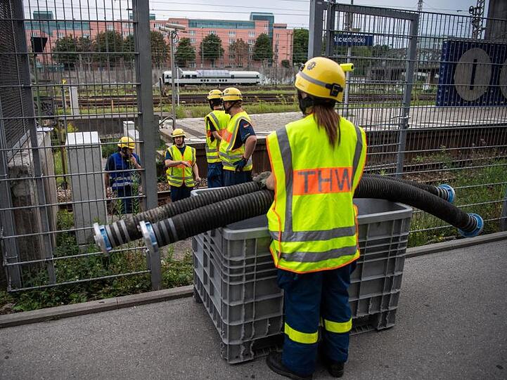 Einsatzkräfte vom THW verlegen Schlauchleitungen auf den S-Bahngleisen in der nähe der Haltestelle Hackerbrücke. Foto: Lino Mirgeler/Archivbild