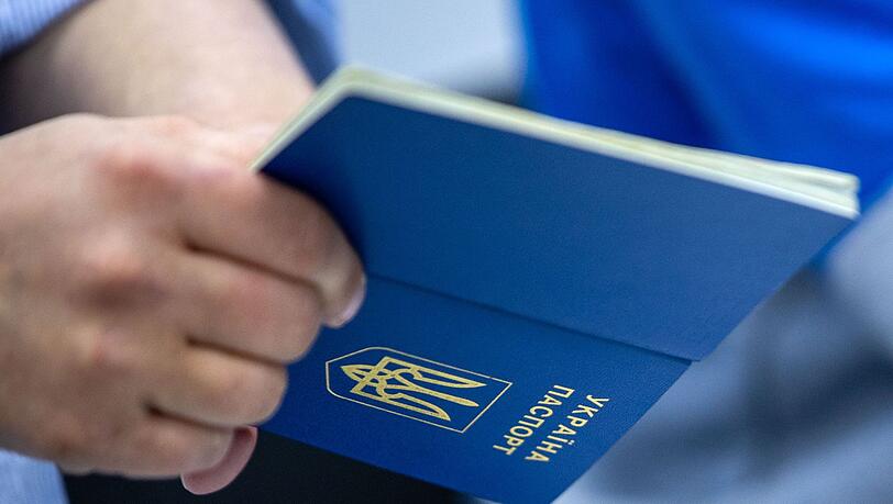 Ein Mann hält einen ukrainischen Reisepass in der Hand.