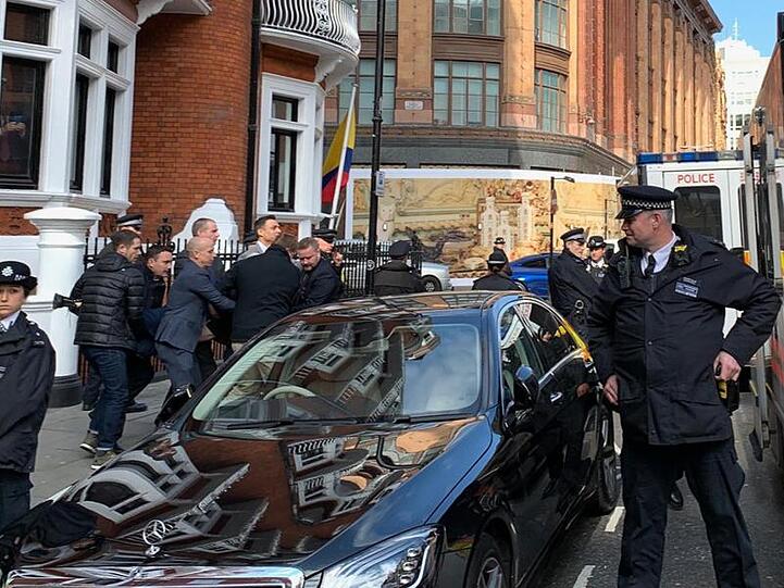 Die Polizei bringt Julian Assange (verdeckt) aus der ecuadorianischen Botschaft heraus.