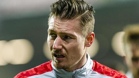 Manuel Schäffler geht vor einem Spiel über den Platz.