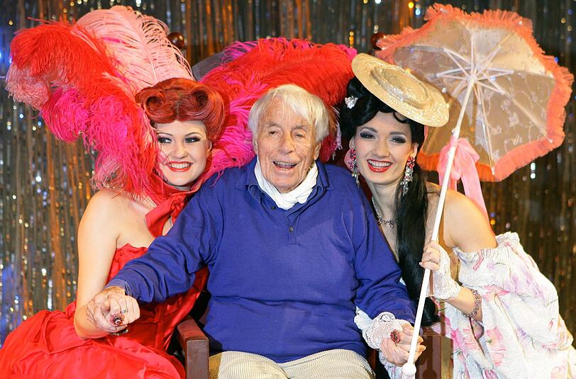 Der Schauspieler und Sänger Johannes Heesters 2006 im Berliner Friedrichstadtpalast zwischen zwei kostümierten Tänzerinnen der Revue Casanova. Er war dort für drei Tage Star-Gast der Show. Für sein Lebenswerk wurde er mit seinen Handabdrücken im Berliner Pflaster vor dem Theatergebäude verewigt.
