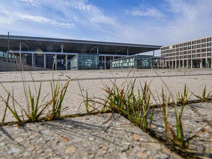 Gras wächst zwischen den Fugen auf einem Platz vor dem Terminal des Hauptstadtflughafens Berlin Brandenburg Willy Brandt (BER).