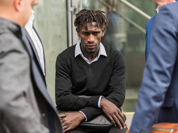Bakery Jatta vom Hamburger SV sitzt auf dem DFB-Gelände auf einer Mauer zwischen HSV-Vertretern.