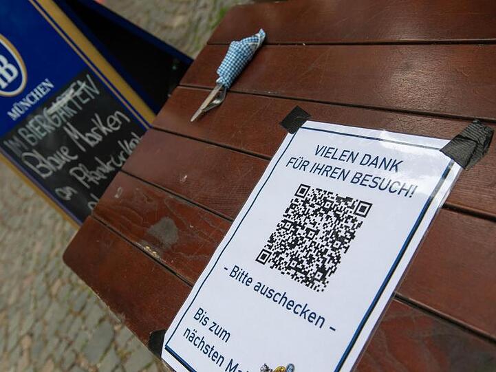 Ein Schild mit einem Barcode klebt auf einem Tisch am Ausgang eines Biergartens. Foto: Peter Kneffel/dpa/Archivbild