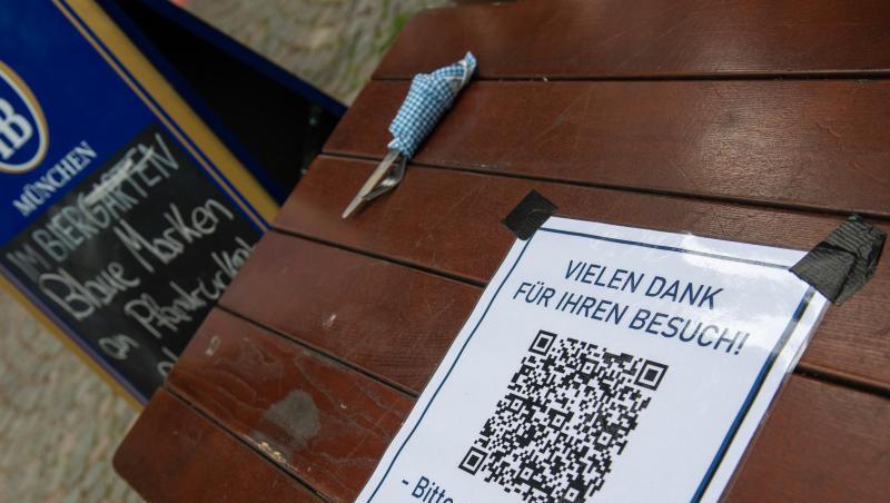 Ein Schild mit einem Barcode klebt auf einem Tisch am Ausgang eines Biergartens. Foto: Peter Kneffel/dpa/Archivbild