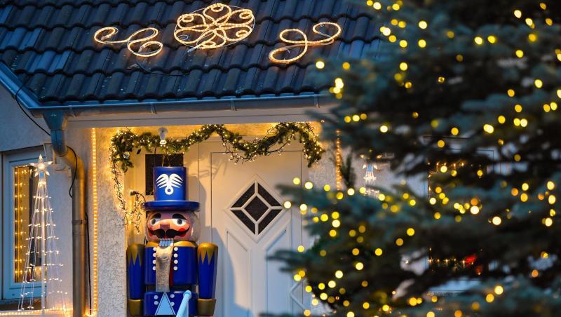 Lichterketten und ein großer Nussknacker stehen an einem weihnachtlich geschmückten Hauseingang. Lichterketten und ein großer Nussknacker stehen an einem weihnachtlich geschmückten Hauseingang.