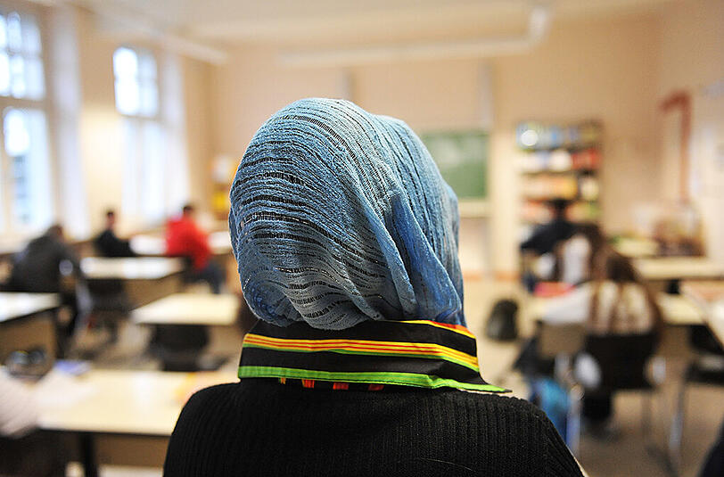 Eine Schülerin mit Kopftuch nimmt am Unterricht in einer Schule teil. Foto: Bernd Thissen/Illustration