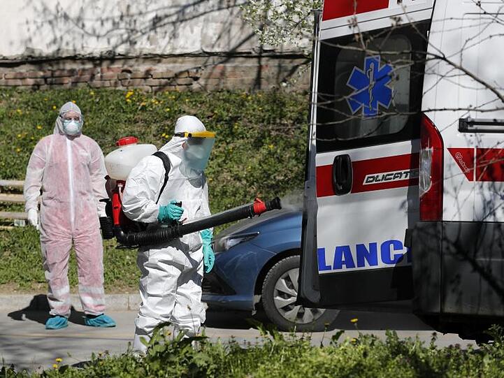 Ein Mann, der Schutzkleidung trägt, desinfiziert in Belgrad einen Krankenwagen. Serbien will die Ausbreitung des Coronavirus mit rigorosen Maßnahmen unterdrücken. Wer das Sars-CoV-2-Virus trägt, aber keine oder nur leichte Symptome hat, soll künftig strikt isoliert werden.