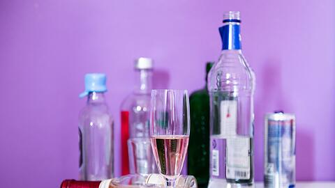 Flaschen mit Alkohol sowie Gläser stehen auf einem Tisch.