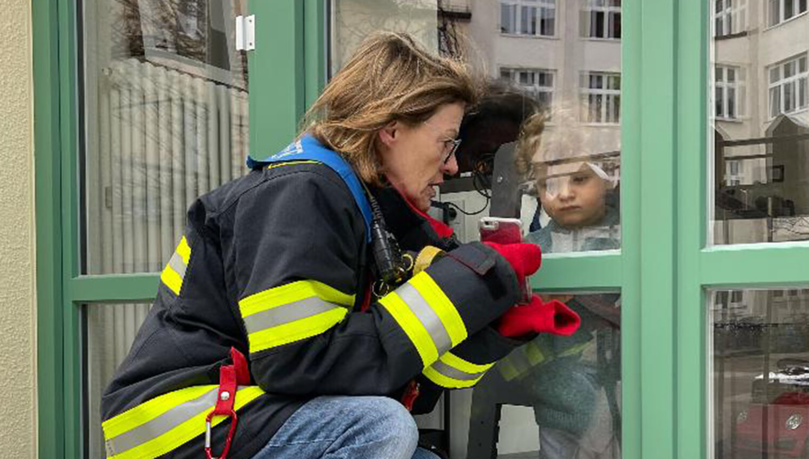 Die Großmutter, gehüllt in eine Feuerwehr-Jacke, mit Enkel Leander.