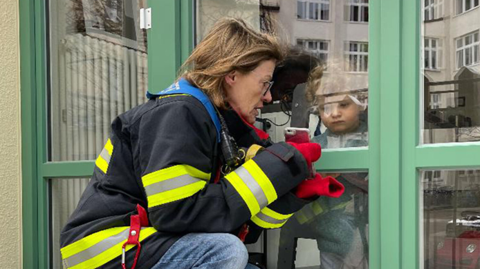 Die Großmutter, gehüllt in eine Feuerwehr-Jacke, mit Enkel Leander.