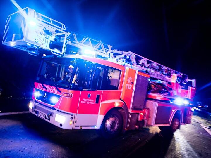Ein Drehleiterwagen der Feuerwehr fährt mit Blaulicht an einer Unfallstelle vorbei. Foto: Marcel Kusch/dpa/Illustration