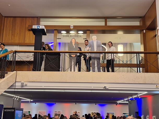 Trump und Harris lächeln auf die Gäste im Foyer des Amerikahauses in München hinab. Trump und Harris lächeln auf die Gäste im Foyer des Amerikahauses in München hinab.