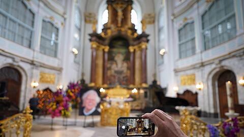 Ein Besucher macht zu Beginn der Trauerfeier ein Foto mit einem Smartphone.