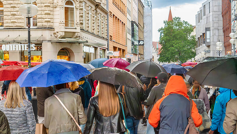Passanten gehen auch bei schlechtem Wetter und mit Regenschirmen in der Kaufingerstraße gerne shoppen. Die Zahl der Laufkundschaft ist hier deutschlandweit an Platz 1.