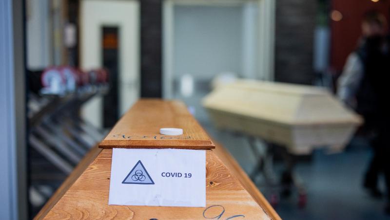 Ein Sarg mit der Aufschrift "Covid 19" und dem Zeichen "Biohazard" steht in einem Krematorium.
