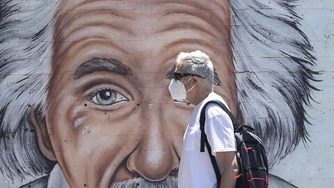 Ein israelischer Mann, der einen Mund- und Nasenschutz trägt, geht an einem Wandbild vorbei, das Albert Einstein zeigt.