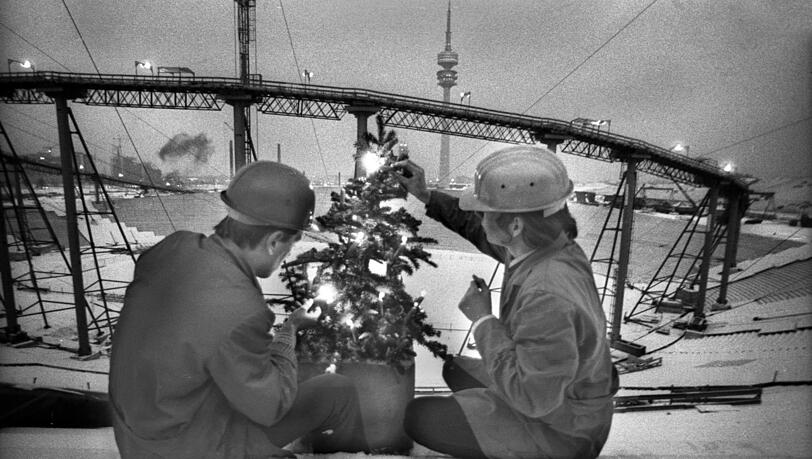 Dezember 1970: Bauarbeiter entzünden einen kleinen Christbaum auf der Haupttribüne des Olympiastadions, das noch eine Großbaustelle ist. Dezember 1970: Bauarbeiter entzünden einen kleinen Christbaum auf der Haupttribüne des Olympiastadions, das noch eine Großbaustelle ist.