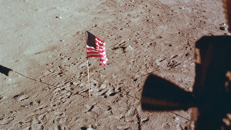 Die Tranquility Base und die US-Flagge sind aus einem Fenster der Mondlandefähre zu sehen.