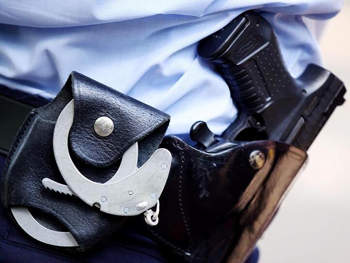 Ein Polizist mit Handschellen und Pistole am Gürtel. Foto: Oliver Berg/dpa
