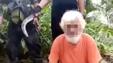 Ein Ausschnitt aus dem Video der Abu Sayyaf. Jürgen K. kniet vor den vermummten und bewaffneten Geiselnehmern. Einer hält einen langen Krummdolch in der Hand.