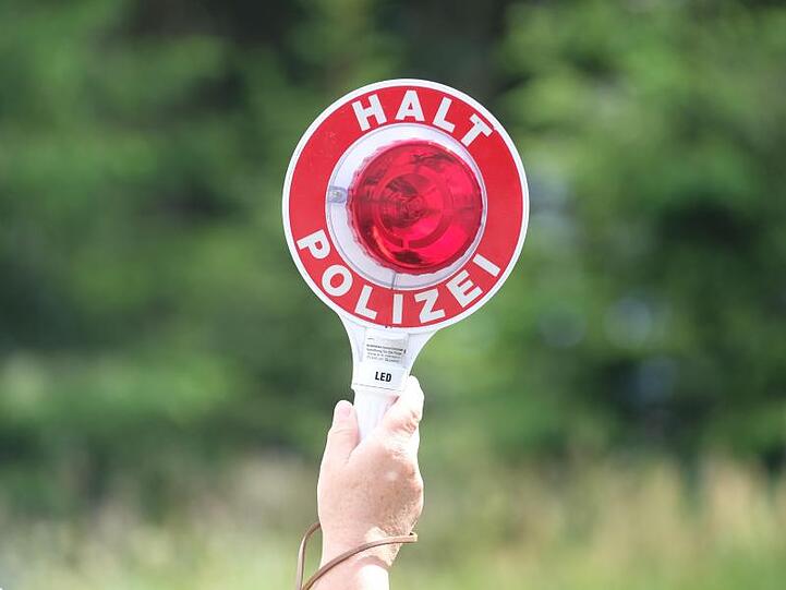 Eine Polizistin hält während einer Polizeikontrolle eine rote Winkerkelle in die Höhe. Foto: Sebastian Willnow/dpa-Zentralbild/dpa/Archiv/Illustration