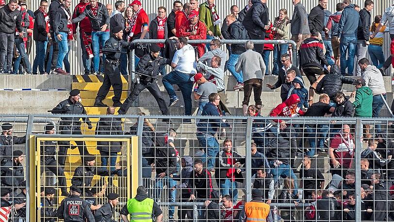 Polizisten mit gezücktem Schlagstock stürmen nach Schlusspfiff in den Gästeblock des Grünwalder Stadions.