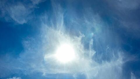 Die Sonne scheint am blauen Himmel durch Wolken hindurch. Foto: Markus Scholz/dpa/Symbolbild