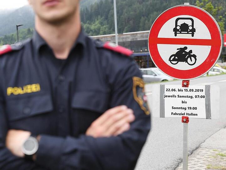 Ein Polizist steht vor einem Schild, das auf die Sperrung für den Verkehr mit Fahrziel Italien hinweist.