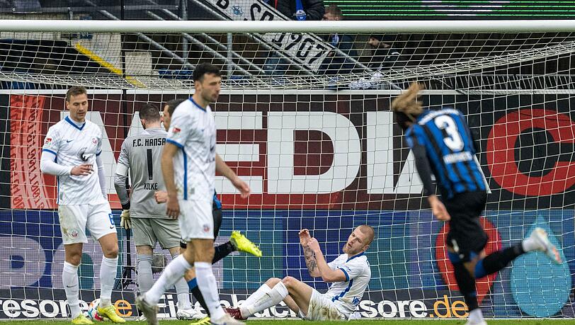 Rostocks Rick van Drongelen (2.v.r.) sitzt nach dem Tor zum 0:1-Rückstand auf dem Rasen.