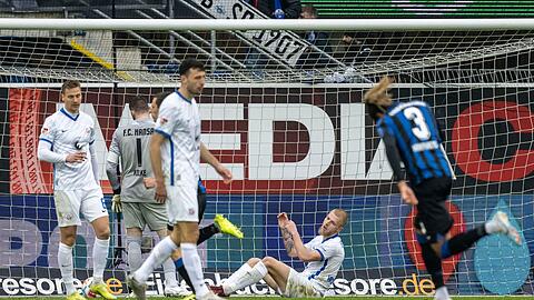Rostocks Rick van Drongelen (2.v.r.) sitzt nach dem Tor zum 0:1-Rückstand auf dem Rasen.